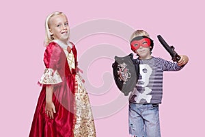 Portrait of young boy and girl in stage costume over pink background