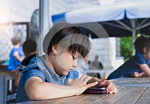 Portrait  young boy playing game on smart phone, Kid boy using mobile phone, School kid waching cartoons on cell phone while