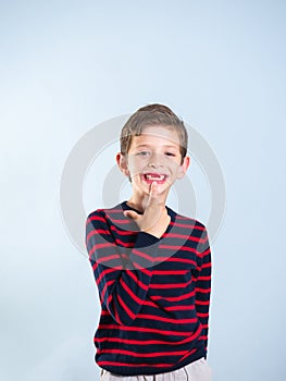 Portrait of a young boy pointing at his missing tooth