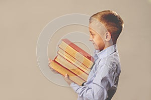 Portrait of young boy of school age with pile of books as symbol of self development and purposefulness. Free space for text