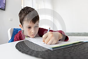 Portrait of young boy struggling with his homework at home. Children home education concept. Distance learning