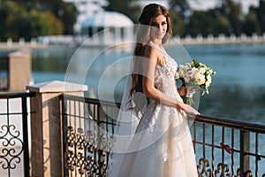 Portrait of young bride with long hairs holding her wedding bouquet includes white roses and other flowers. Beautiful