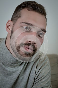 Portrait of a young brown-haired man with a short beard and a gray turtleneck sweater