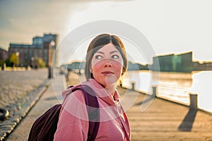 Portrait of a young brunette girl who stands on the canal embankment at sunset. Copenhagen, Denmark