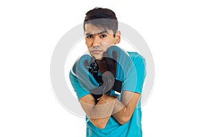 Portrait of young brunette man in blue gloves practicing boxing and looking at the camera isolated on white background
