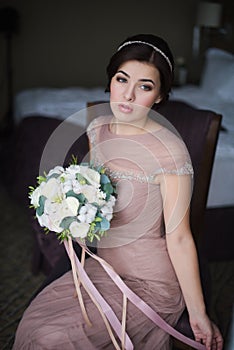 Portrait of a young brunette woman in a beautiful dress with make-up and hairstyle