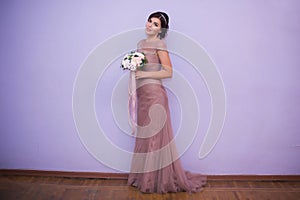 Portrait of a young brunette woman in a beautiful dress with make-up and hairstyle