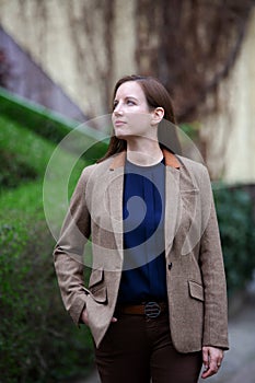 Portrait young brunette woman in brown jacket standing in front of building