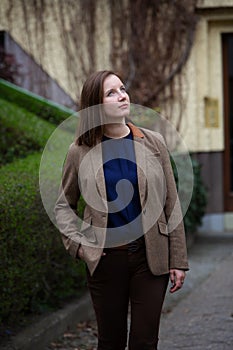 Portrait young brunette woman in brown suit standing in front of building