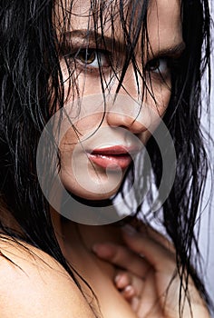 Portrait of a young brunette woman with hining wet make-up and s