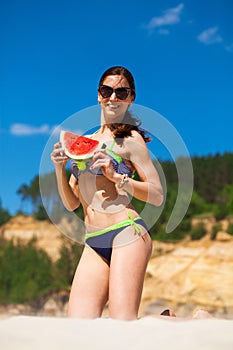 Portrait of a young brunette woman with a juicy slice of watermelon