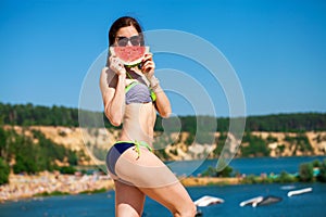 Portrait of a young brunette woman with a juicy slice of watermelon