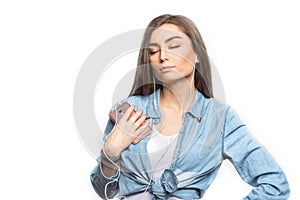 Portrait of a young brunette woman listening to the music with her eyes closed against white background, isolated.