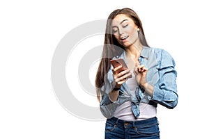 Portrait of a young brunette woman looking at the smartphone with surprised expression on her face against white background