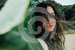 Portrait young brunette woman with tropical palm tree leaf