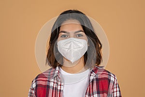 Portrait of young brunette woman wearing white face mask