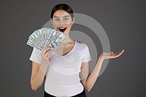 Portrait of young brunette woman in whote t-shirt holding money banknotes and celebrating