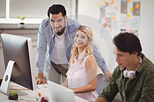 Portrait of young business colleagues working on desktop pc at office desk