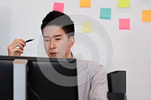Portrait of Young business indian man working with laptop thinking business plan and holding pen