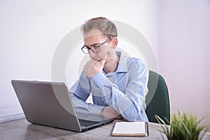 Portrait of young business man sitting at his desk desktop laptop technology in the office.Internet marketing, finance, business