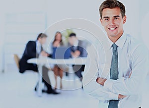 Portrait of young business man smiling with colleagues in background.