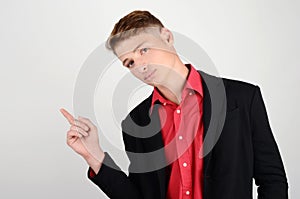 Portrait of a young business man wearing a suit and a red shirt pointing to the side.