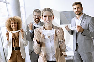 Portrait of young business people taking off their protective face masks