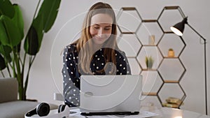 Portrait of a young business woman dancing while sitting at her desk. A successful and happy woman celebrates record