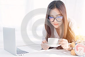 Portrait of a young business woman ,laptop,cup of coffee. Business concept a laptop drinking coffee with her computer on the bed