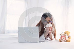 Portrait of a young business woman ,laptop,cup of coffee. Business concept a laptop drinking coffee with her computer on the bed