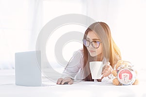 Portrait of a young business woman ,laptop,cup of coffee. Business concept a laptop drinking coffee with her computer on the bed