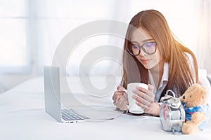 Portrait of a young business woman ,laptop,cup of coffee. Business concept a laptop drinking coffee with her computer on the bed