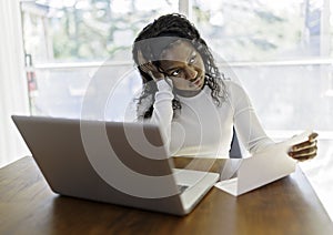 Portrait of a young business woman with laptop working on the kitchen table look sad because of bill to pay