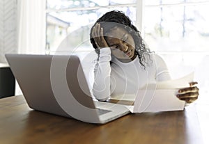 Portrait of a young business woman with laptop working on the kitchen table look sad because of bill to pay