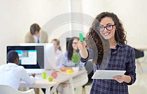 Portrait of young business woman at modern startup office interior, team in meeting in background