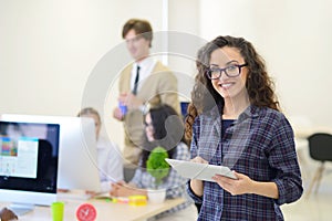 Portrait of young business woman at modern startup office interior, team in meeting in background