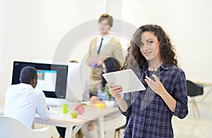 Portrait of young business woman at modern startup office interior, team in meeting in background