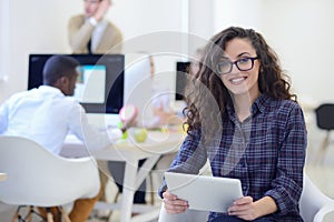 Portrait of young business woman at modern startup office interior, team in meeting in background