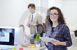 Portrait of young business woman at modern startup office interior, team in meeting in background