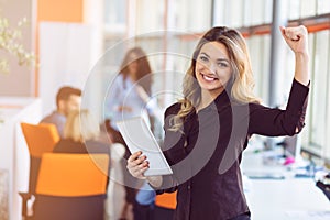 Portrait of young business woman at modern startup office interior, team in meeting in background