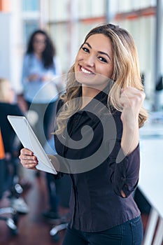 Portrait of young business woman at modern startup office interior, team in meeting in background