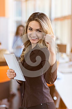 Portrait of young business woman at modern startup office interior, team in meeting in background