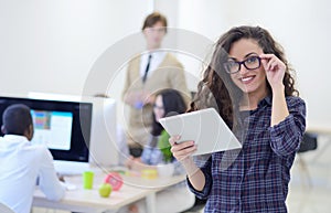 Portrait of young business woman at modern startup office interior, team in meeting in background