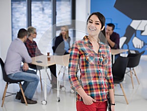 portrait of young business woman at office with team in background