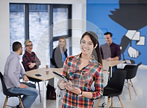 portrait of young business woman at office with team in background