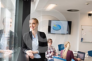 Portrait of young business woman at office with team on meeting