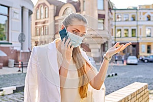 Portrait of young business woman in medical protective mask talking on cellphone