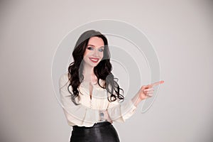 Portrait of Young business woman points her finger at gray isolated background