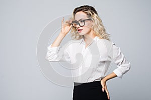 Portrait of young business woman wearing glasses isolated on grey background.