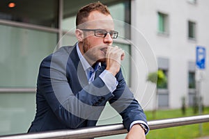 Portrait of young businessman with beard standing in front of of